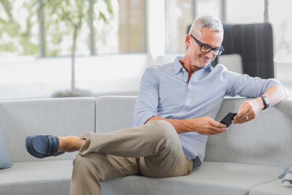 Man sitting on couch while browsing phone